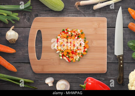 Chopped vegetables on cutting board. Onion, mushrooms, carrot, pepper beside. Stock Photo