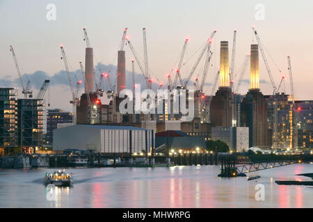 Large construction cranes surround Battersea Power Station on the south bank of the River Thames in West London where a major regeneration project on  Stock Photo