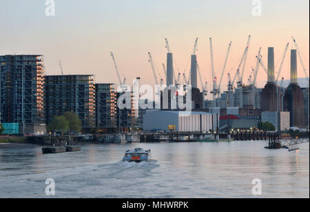 A Thames Clipper makes it way past the large construction cranes surrounding Battersea Power Station on the south bank of the River Thames in West Lon Stock Photo