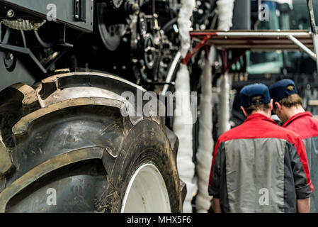 Worker assembles tractor or combine harvester at large machinery plant. Industrial concept of heavy machinery manufacturing Stock Photo