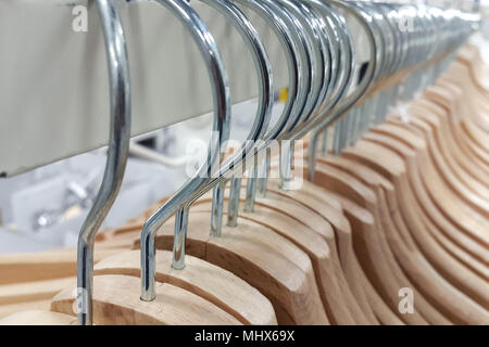 Many wooden hangers for clothes stacked on a store rack. Stock Photo