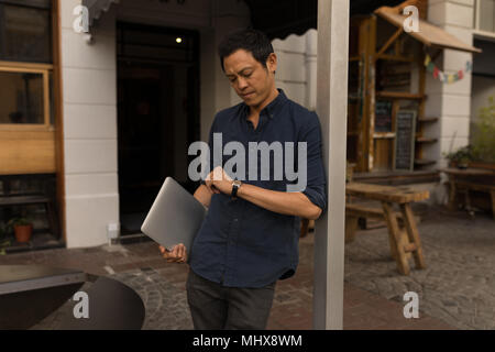 Businessman with laptop checking his smartwatch Stock Photo