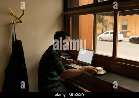 Businessman using laptop while having coffee Stock Photo