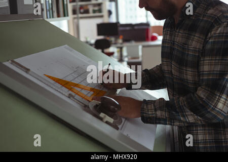 Architect working on blueprint on drafting table Stock Photo