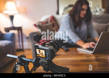 Female vlogger sitting on sofa while using laptop Stock Photo