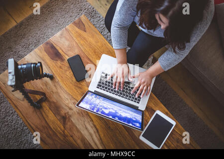 Female vlogger sitting on sofa while using laptop Stock Photo