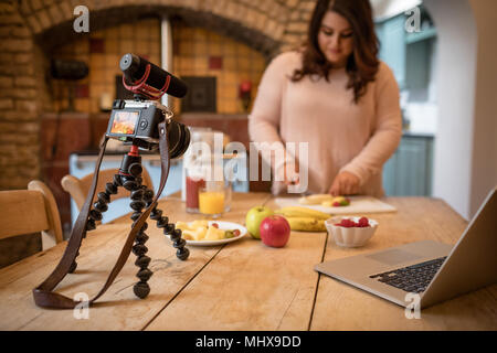 Female vlogger cutting fruit on chopping board Stock Photo