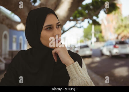 Thoughtful hijab woman at pavement cafe Stock Photo