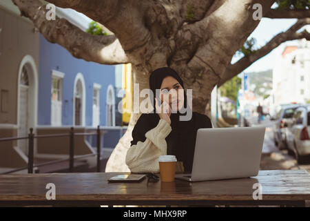 Urban hijab woman talking on mobile phone at cafe Stock Photo