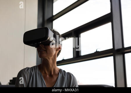 Mature businesswoman using virtual reality headset Stock Photo