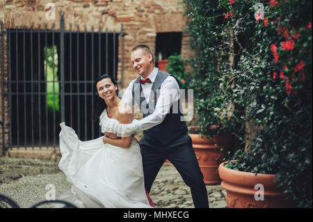 Laughing wedding couple stands in the rays of sunshine Stock Photo