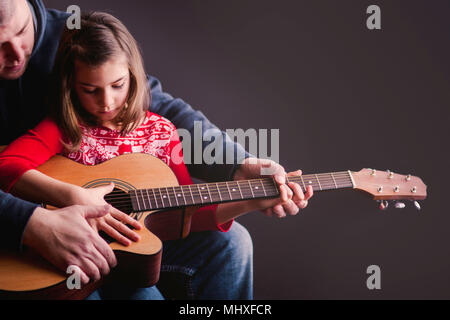 Father teaching daughter to play guitar