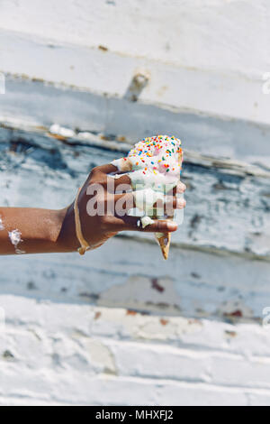 Woman holding melting, dripping ice cream cone, close up of hand Stock Photo