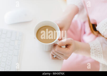 Young woman sitting at computer holding coffee mug, overhead close up view Stock Photo