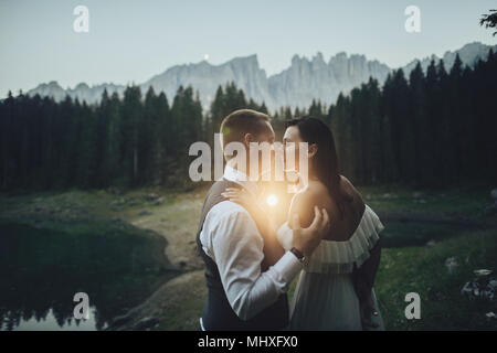 Happy stylish couple in summer alpine meadows in Italy. Kissing bride and groom Stock Photo