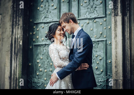 newly wedded couple posing near antique green door Stock Photo