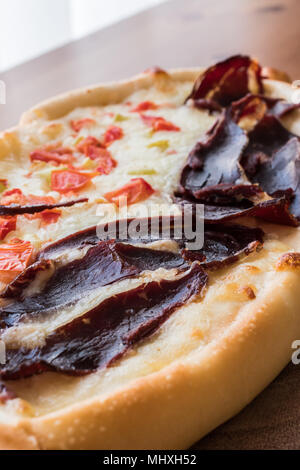 Turkish Pide with Pastirma , tomato and melted cheese on a wooden surface. Turkish Pide with Pastirma , tomato and melted cheese on a wooden surface.