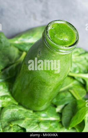 Bottle with Green Fresh Raw Smoothie from Leafy Greens Vegetables Fruits Apples Bananas Kiwi Zucchini on Spinach Leaves as Background. Healthy Lifesty Stock Photo