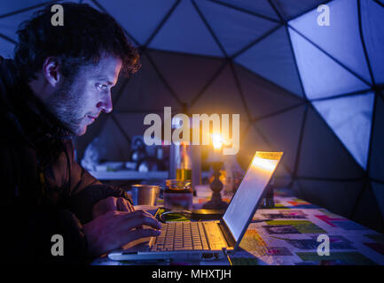 Man on expedition, using laptop in camp, Fletanes camp, Narsaq, Kitaa, Greenland Stock Photo