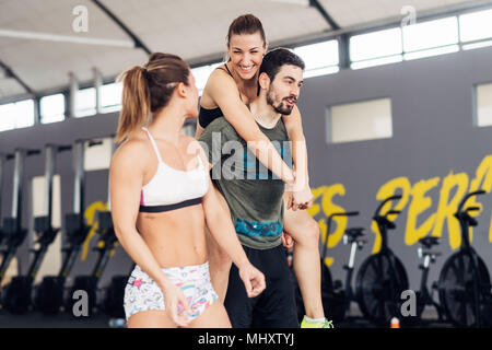 Man giving woman piggy back in gym Stock Photo