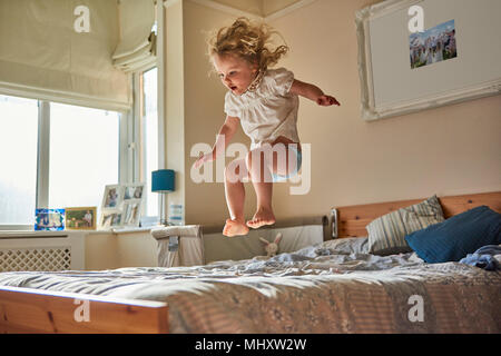 Female toddler jumping mid air on bed Stock Photo