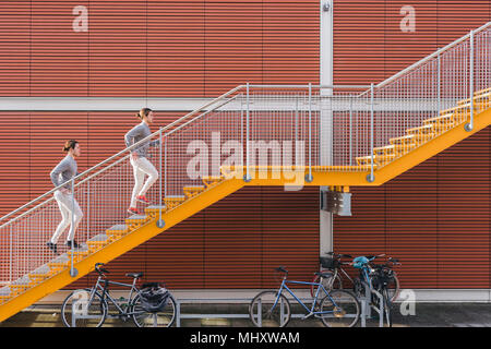 Young adult male twins running together, running up city stairs Stock Photo