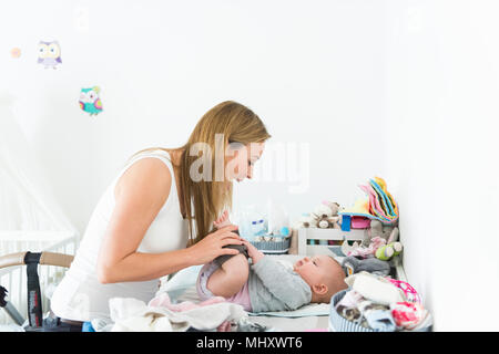 Mother playing with baby on changing table Stock Photo