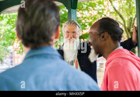 Three mature men, standing under bandstand, talking Stock Photo