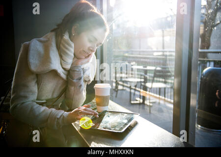 Young girl sitting in coffee shop, using digital tablet, London, England, UK Stock Photo