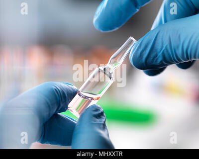 Doctor preparing a experimental drug held in a ampule during a medical trial Stock Photo