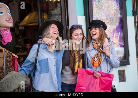 Friends leaving clothing shop smiling Stock Photo