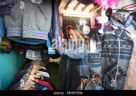 Young woman browsing vintage clothes in thrift store