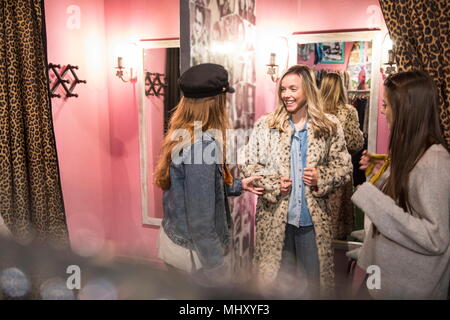 Friends trying on vintage clothes in thrift store Stock Photo