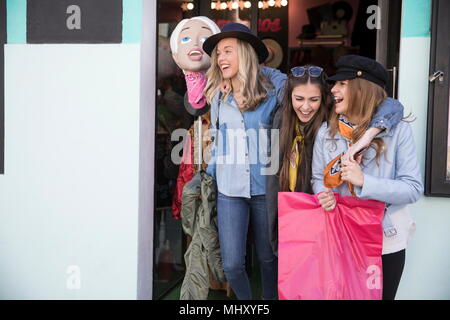 Friends leaving clothing shop smiling Stock Photo