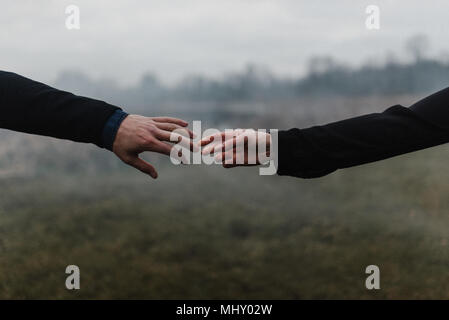 Cropped view of young couple holding hands, fingers touching Stock Photo