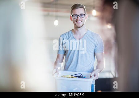 Computer technician with box of cables in office, portrait Stock Photo