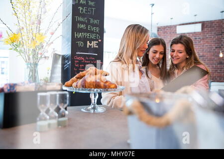 Three female friends, looking at menu in cafe