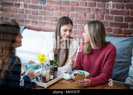 Three female friends, sitting together in cafe Stock Photo