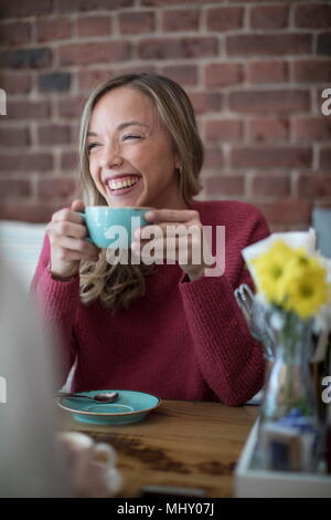 Woman sitting in cafe, drinking coffee, smiling