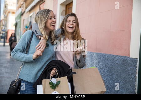 Friends out shopping and laughing in street Stock Photo