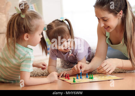 Happy family. Young mother playing ludo boardgame with her daughters while spending time together at home. Stock Photo