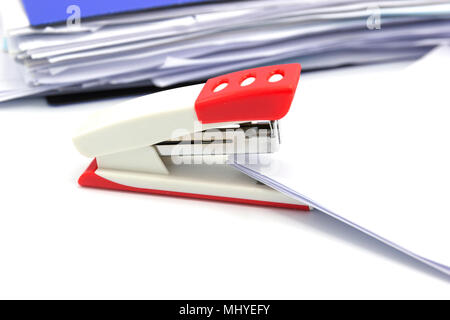 Pink stapler and paper document on white background, Office equipment. Stock Photo