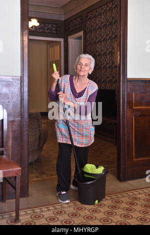 Older woman with mop making the floor of her house Stock Photo