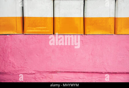 painted tin cans decoratively arranged on a pink textured wall with copy space Stock Photo