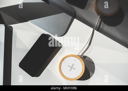 Mobile phone and wireless charger on office table. Future technology concept. Stock Photo