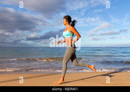 Hispanic female runs at the beach in Kihei, Maui, Hawaii. Stock Photo