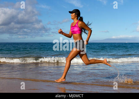 Hispanic female runs at the beach in Kihei, Maui, Hawaii. Stock Photo