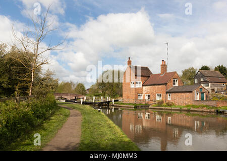 The lock keepers cottage, adjacent to a lock on the Grand Junction Canal, reflects in the water. Stock Photo