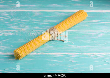 Spaghetti tied with a rope on blue rustic wooden table Stock Photo