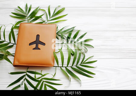 summer vacation concept, image above with space for text. passport with plane on green palm leaves on white wooden background. modern travel and wande Stock Photo